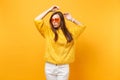 Portrait of relaxed young woman in fur sweater, white pants and heart orange glasses rising hands up isolated on bright Royalty Free Stock Photo