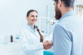 Portrait of a reliable and cheerful dentist shaking the hand of a patient