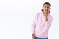 Portrait of reluctant handsome blond man in pink hoodie, yawning with opened mouth and closed eyes, cover it with arm Royalty Free Stock Photo