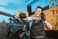 Portrait of a repairman in an apron getting a call via cellphone while repairing a bicycle