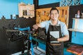 Portrait of a repairman in an apron leaning on a bicycle frame while holding a tablet