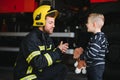 Portrait of rescued little boy with firefighter man standing near fire truck. Firefighter in fire fighting operation. Royalty Free Stock Photo