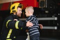 Portrait of rescued little boy with firefighter man standing near fire truck. Firefighter in fire fighting operation. Royalty Free Stock Photo