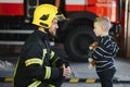 Portrait of rescued little boy with firefighter man standing near fire truck. Firefighter in fire fighting operation. Royalty Free Stock Photo