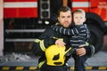 Portrait of rescued little boy with firefighter man standing near fire truck. Firefighter in fire fighting operation. Royalty Free Stock Photo