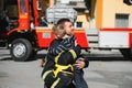 Portrait of rescued little boy with firefighter man standing near fire truck. Firefighter in fire fighting operation.