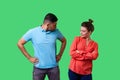Portrait of resentful dissatisfied couple in casual wear standing together. isolated on green background