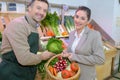 Portrait retailer and customer holding basket fresh vegetables