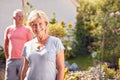 Portrait Of Retired Couple Working In And Enjoying Summer Garden At Home