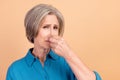 Portrait of retired person with white gray hairdo wear blue shirt fingers close nose from stinky smell isolated on