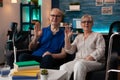 Portrait of retirement couple sitting on couch waving hands Royalty Free Stock Photo