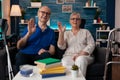 Portrait of retirement couple sitting on couch waving hands