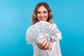 Portrait of rich beautiful woman showing dollars and smiling happily. isolated on blue background