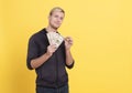 Portrait of rich man holding dollar money isolated over yellow background