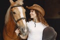 Portrait of rider woman in a leather hat with a brown horse in a stable Royalty Free Stock Photo