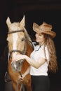 Portrait of rider woman in a leather hat with a brown horse in a stable Royalty Free Stock Photo