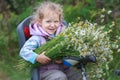 Portrait of riding on bicycle child seat little blonde girl with bouquet of wild chamomiles in hands