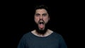 Portrait of roar handsome man with beard standing and screaming with big open mouth, isolated on black background. Young Royalty Free Stock Photo