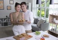 Asian couple is cooking on kitchen and looking at camera. Young man and young woman are having fun together while prepare food. Royalty Free Stock Photo