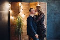 Portrait of romantic couple sitting on grey couch in decorated studio.