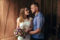 Portrait of a romantic couple,man and woman kissing in a dramatic light, girl holding flowers in hands, young beautiful bride in w