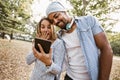 Portrait of romantic and happy mixed race young couple in park using digital tablet Royalty Free Stock Photo