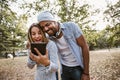 Portrait of romantic and happy mixed race young couple in park using digital tablet Royalty Free Stock Photo