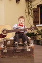 Portrait of a romantic little boy sitting with guitar.