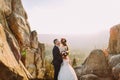 Portrait of romantic newlywed couple going to kiss in sunset lights on majestic mountain landscape with big rocks as Royalty Free Stock Photo