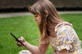 Portrait of romantic young woman using her phone on the grass