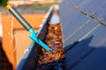 A portrait of a roof gutter full of fallen brown autumn leaves on a sunny day with a small blue garden shovel in it of someone who Royalty Free Stock Photo