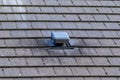 A portrait of a roof vent on a slate roof on a house. This small chimney like object is used as a ventilation, to ventilate a