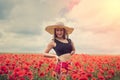 portrait of rpetty ukrainian woman in black top and hat with big bouquet of poppies in field