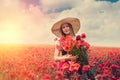 portrait of rpetty ukrainian woman in black top and hat with big bouquet of poppies in field