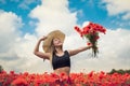 portrait of rpetty ukrainian woman in black top and hat with big bouquet of poppies in field