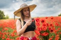 portrait of rpetty ukrainian woman in black top and hat with big bouquet of poppies in field