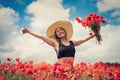 portrait of rpetty ukrainian woman in black top and hat with big bouquet of poppies in field