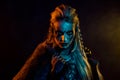 Portrait of ruthless mysterious viking girl angry glance yellow blue lights mist isolated on black color background