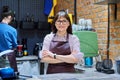 Female business owner in apron standing behind bar counter in coffee shop cafeteria Royalty Free Stock Photo