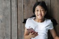 Long hair kid girl with white t-shirt with mobile smart phone listen to the music by white earphone lay down on Royalty Free Stock Photo