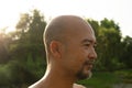 Portrait of 40s topless Asian Japanese skin head bald beard man in green sunlight summer nature tree background