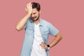 Portrait of sad alone loser bearded young man in blue casual style shirt standing holding his head down and thinking what to do