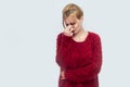 Portrait of sad alone or tired beautiful young blond woman in red blouse standing, holding head down and crying with trouble and Royalty Free Stock Photo