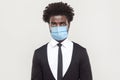 Portrait of sad alone young handsome worker man in black suit with surgical medical mask standing and looking at camera with tired