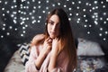 Portrait of sad attractive young woman with tinsel confetti and garland lights celebrating alonein dark room. New year`s Royalty Free Stock Photo