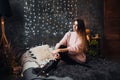 Portrait of sad attractive young woman with tinsel confetti and garland lights celebrating alonein dark room. New year`s Royalty Free Stock Photo