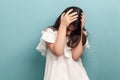 Portrait of sad beautiful brunette young girl with black long straight hair in white dress standing holding her head down and Royalty Free Stock Photo