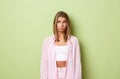 Portrait of sad blond girl in pink shirt, looking upset at upper left corner and sulking disappointed, standing over Royalty Free Stock Photo