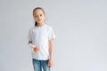 Portrait of sad blonde little girl with broken hand wrapped in white plaster bandage standing on white isolated Royalty Free Stock Photo