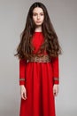 Portrait of a sad brunette girl with long hair in a red dress Royalty Free Stock Photo